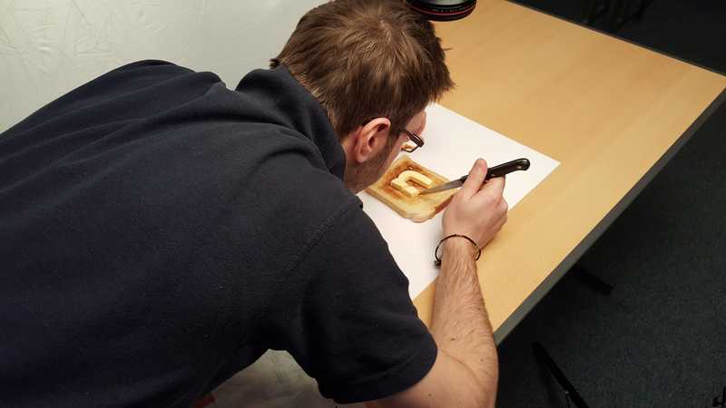 Steve repositions a butter logo into the middle of a piece of toast with a sharp knife.